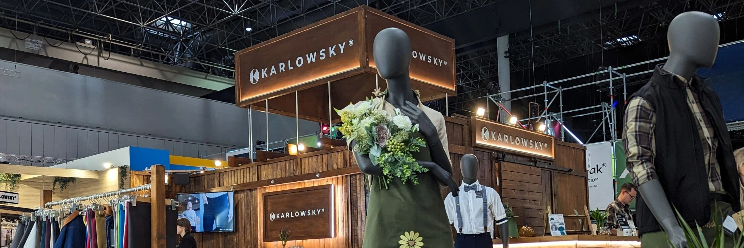 Messestand aus Holz auf der A+A Messe. Im Vordergrund ist eine Floristin Schaufensterpuppe. Im Hintergrund ist ein Großes Schild mit der Aufsschrift "Karlowsky" 