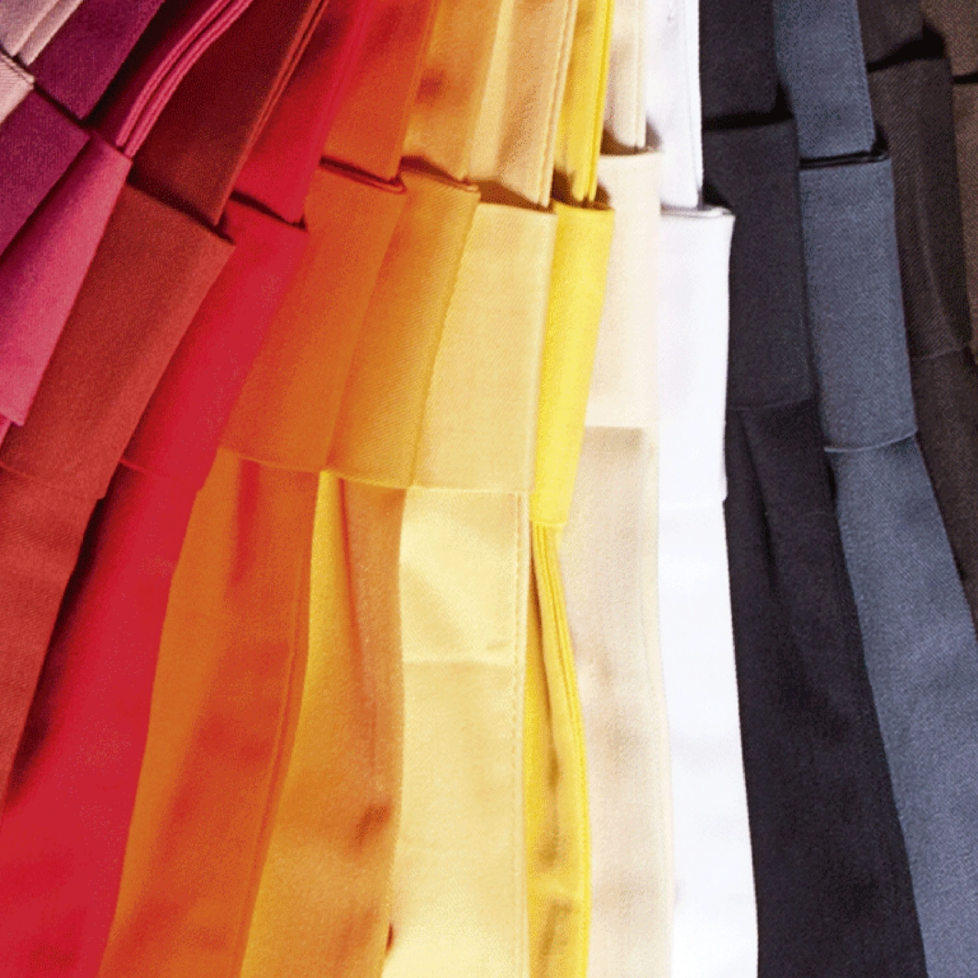 Bunte Schürzenvielfalt Hochformat Viele bunte Schürzen sind wie ein Fächer übereinander gefaltet.
